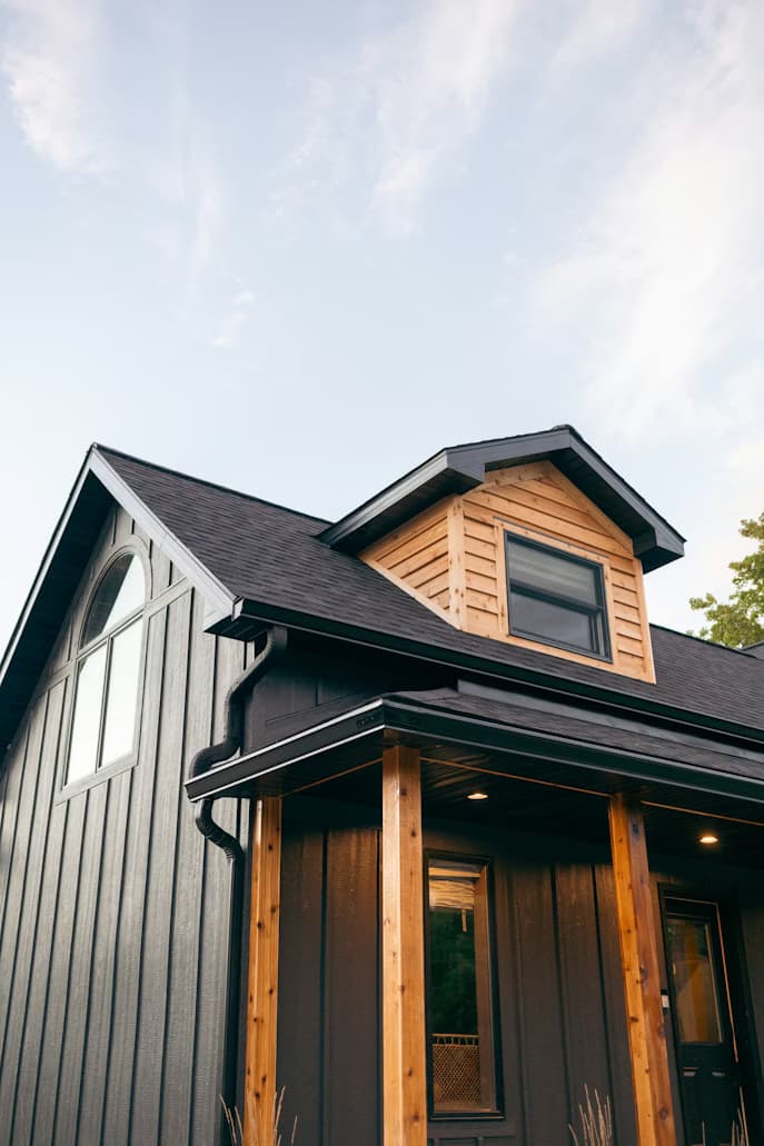 A finished home with a freshly installed black roof and wooden trim — the kind of work pros showcase to clients in their portal